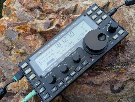 Elecraft KX3 transceiver, tuned to 17m amateur radio band, 18.127MHz USB. Underneath, rock surface covered with lichen.